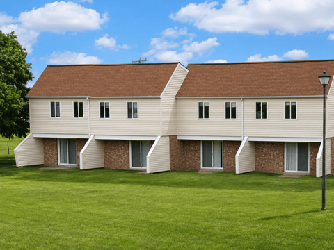 A white building with a brown roof and a green lawn in front.