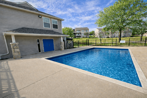 A residential house with a blue door and a pool in the backyard.