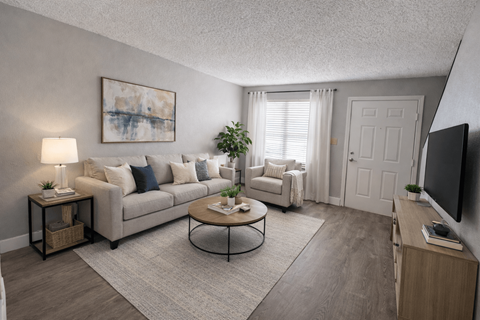 A living room with a grey couch, a coffee table, a lamp, a plant, and a painting on the wall.