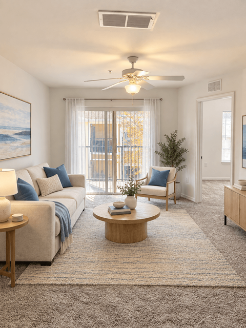 A living room with tan carpeting, white walls, and a sliding doors at the back to a patio or balcony