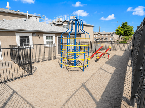 A playground with a blue and yellow structure and a red slide.