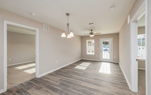 A spacious room with a light wooden floor and a ceiling fan.