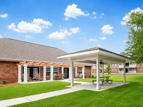 A covered patio area with a picnic table in front of a brick building.