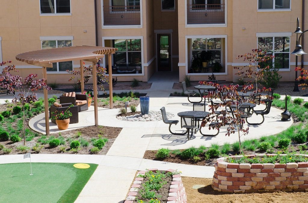 A patio with a table and chairs is surrounded by a garden.
