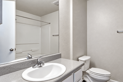 A white bathroom with a sink, toilet, and shower.