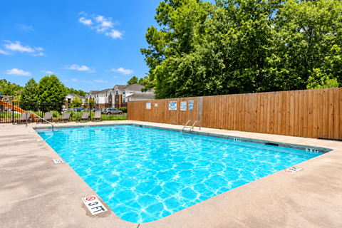 A large outdoor swimming pool surrounded by a wooden fence.