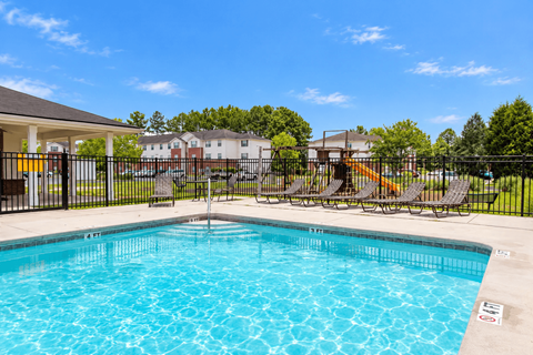 A swimming pool surrounded by a black fence and chairs.