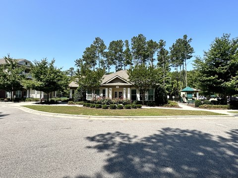 a house on the corner of a roundabout in front of some trees