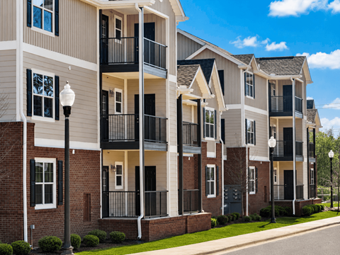 A row of modern apartment buildings with balconies and black railings.
