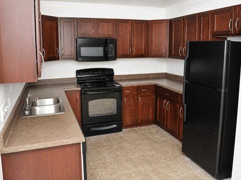 A kitchen with black appliances and wooden cabinets.