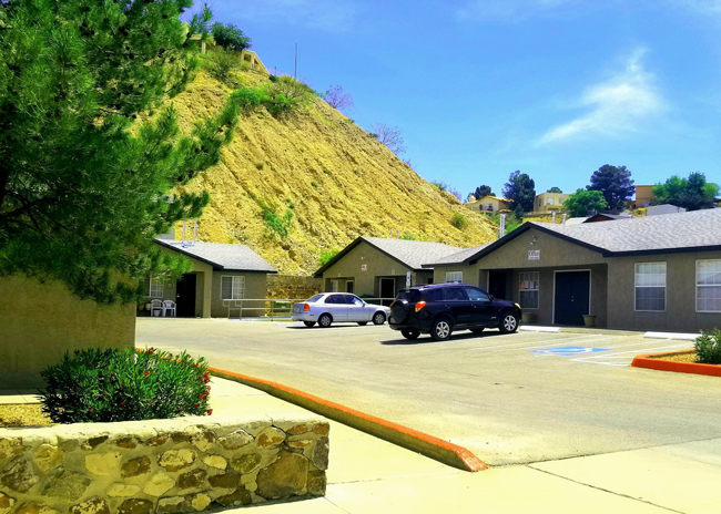 a parking lot in front of a house with a hill in the background