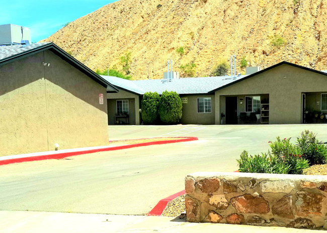 a building with a mountain in the background and a parking lot