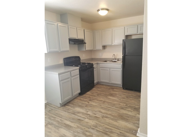 a kitchen with white cabinets and a black refrigerator
