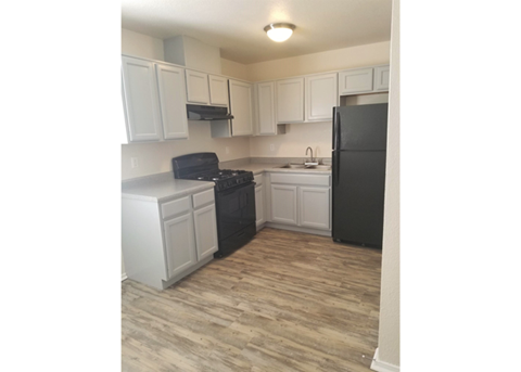a kitchen with white cabinets and a black refrigerator