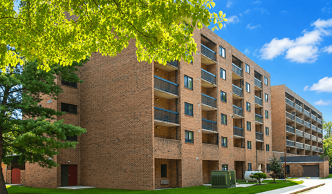 A large brick building with balconies and a tree in front.