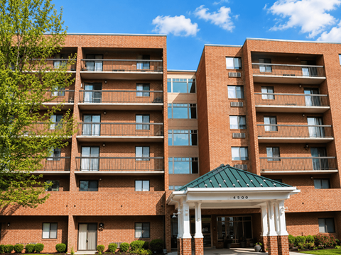 A large brick building with a green roof and a covered walkway entrance.