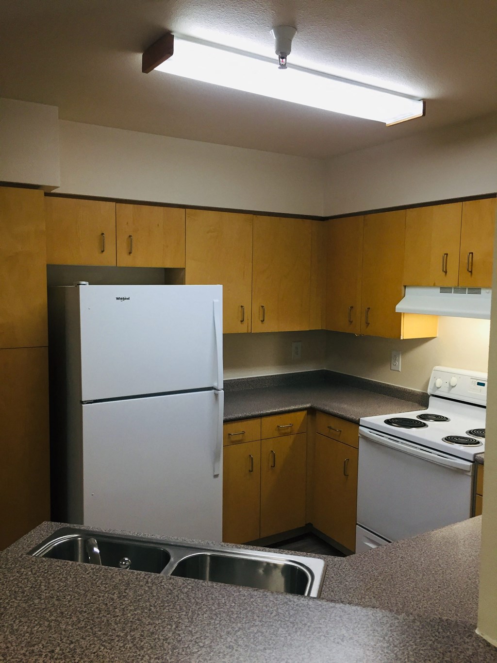 an empty kitchen with white appliances and wooden cabinets