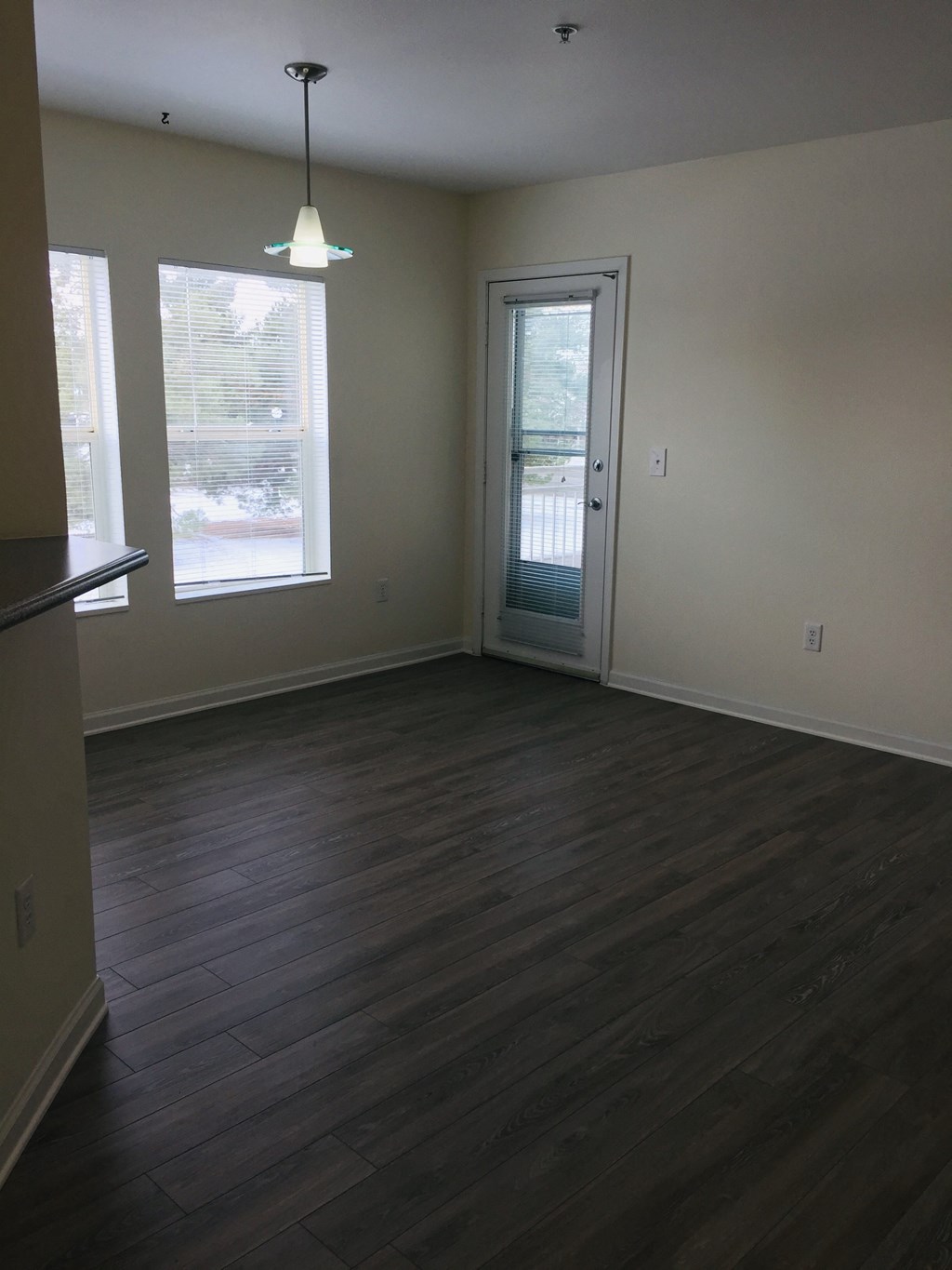 an empty living room with wood floors and a door to a balcony