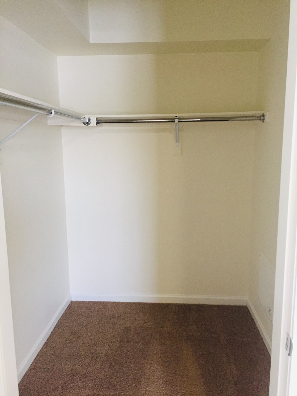 a empty closet in a white room with a rail on the wall