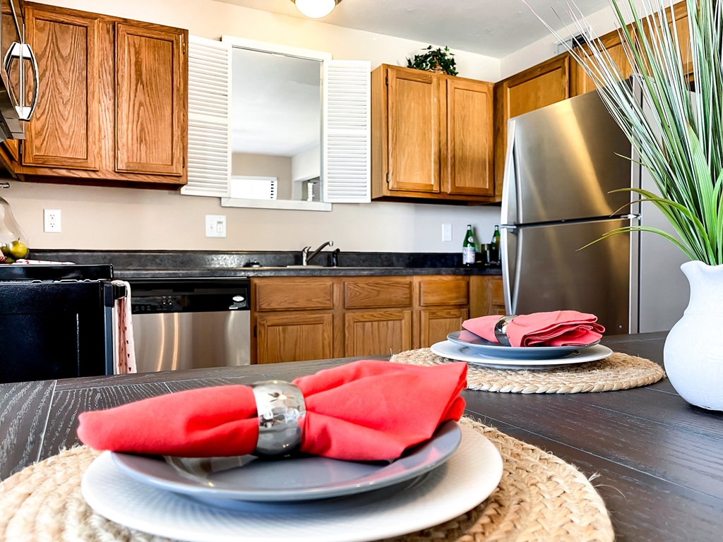 a kitchen with stainless steel appliances and a table with plates and napkins on it