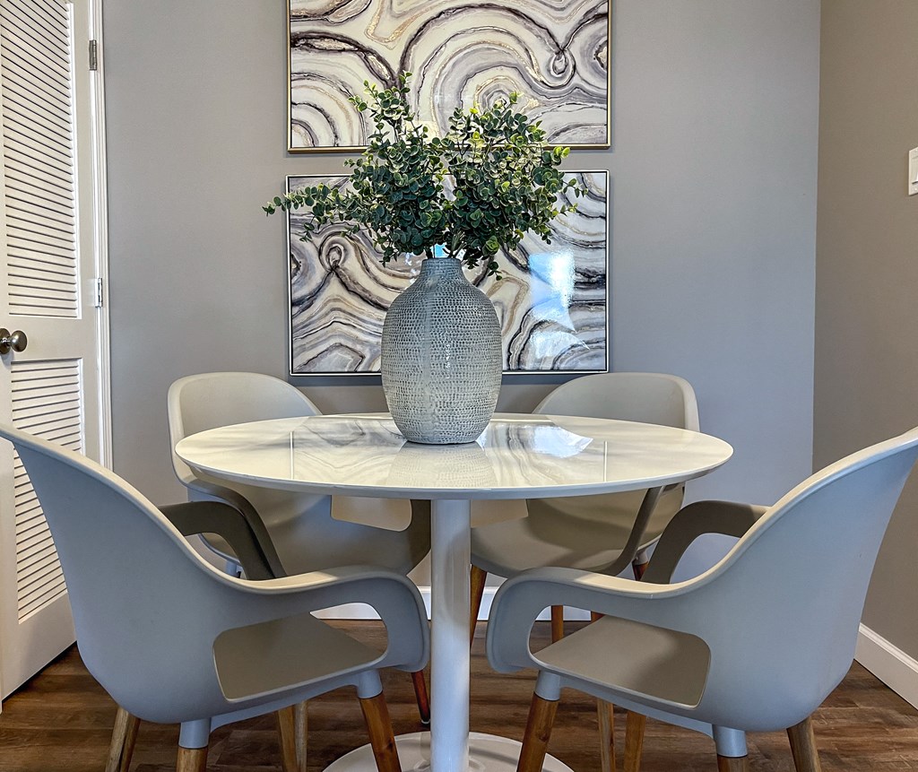 a dining room with a table and chairs and a vase with flowers