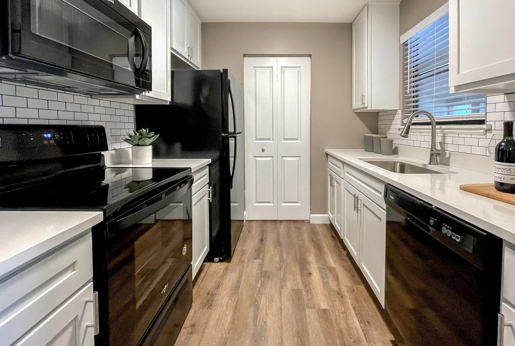 a kitchen with white cabinets and black appliances