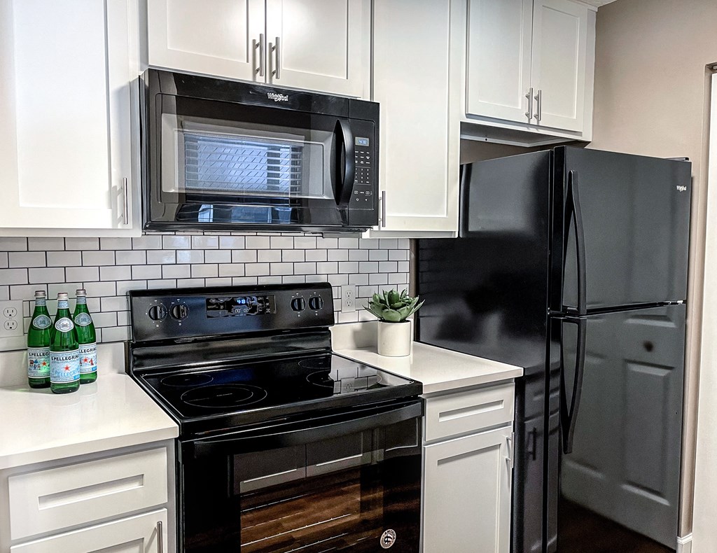 a kitchen with black appliances and white cabinets and a black refrigerator