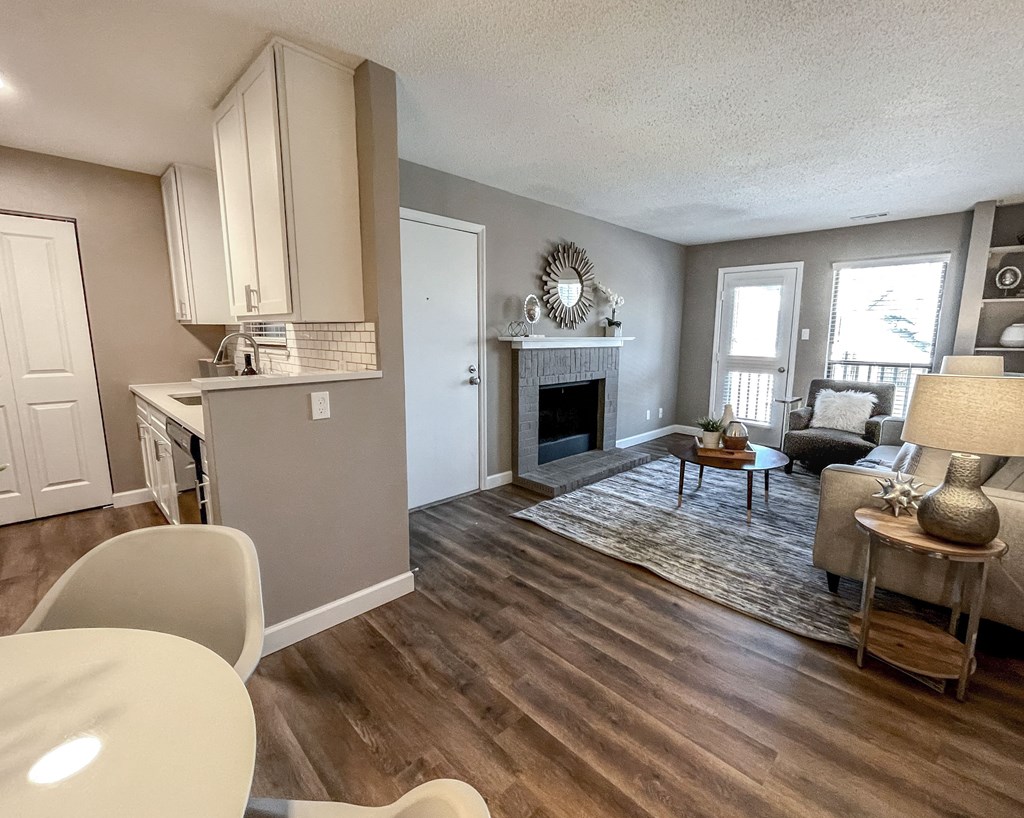 the view of the living room from the dining room and the kitchen with a fireplace