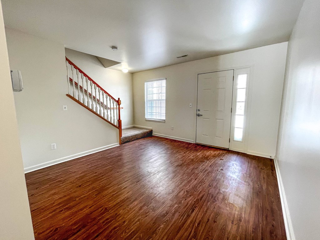 an empty living room with hard wood floors and a white door