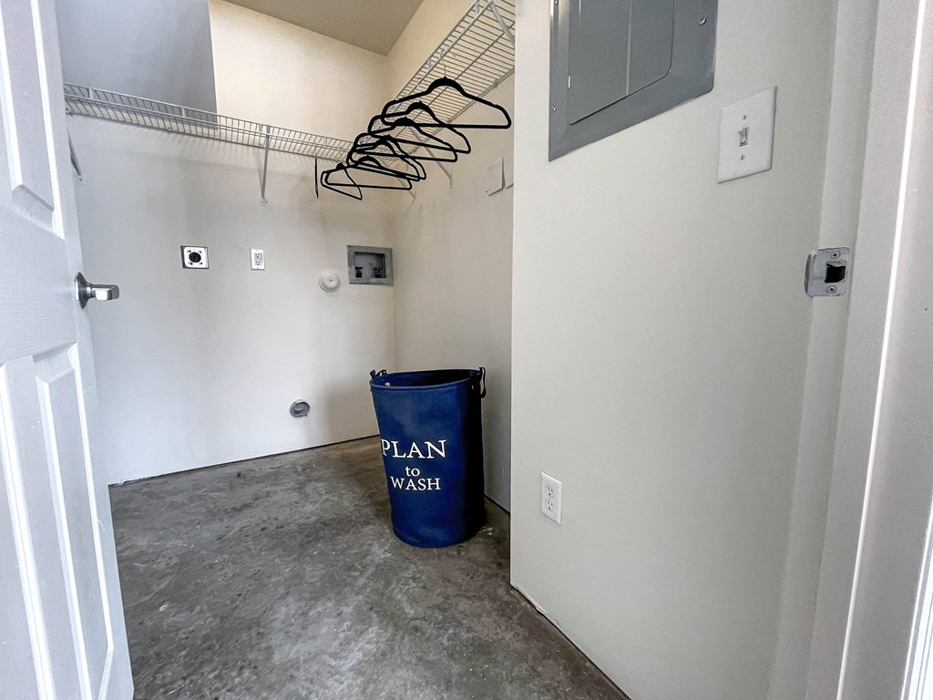 an empty room with a trash can and a plan in the closet