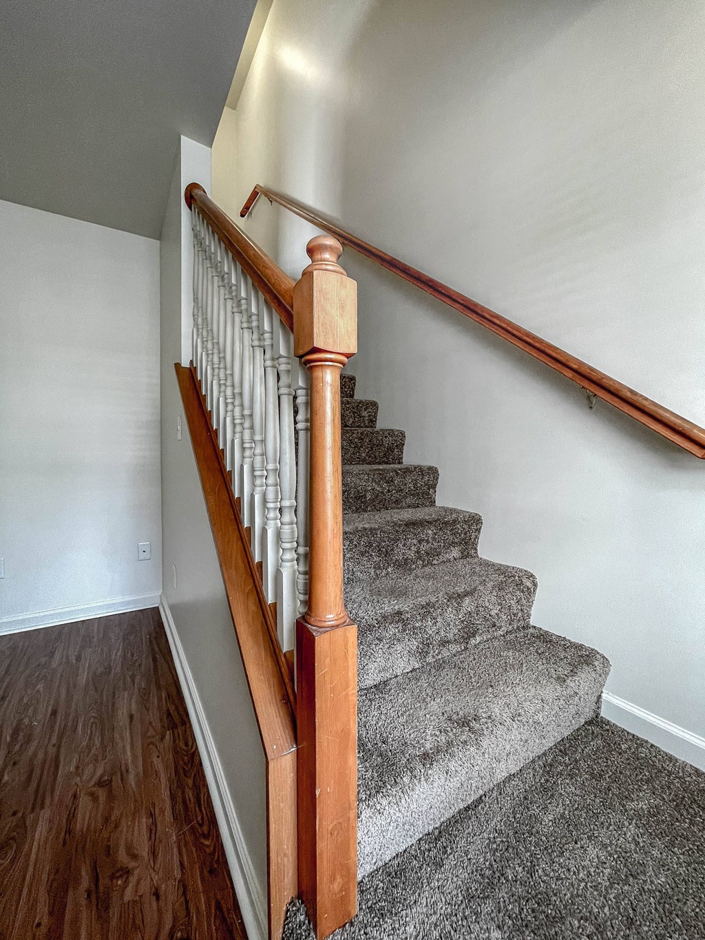 a carpeted staircase with wood railings in a home with white walls