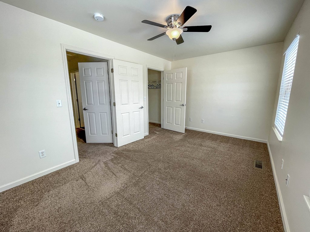 an empty living room with carpet and a ceiling fan