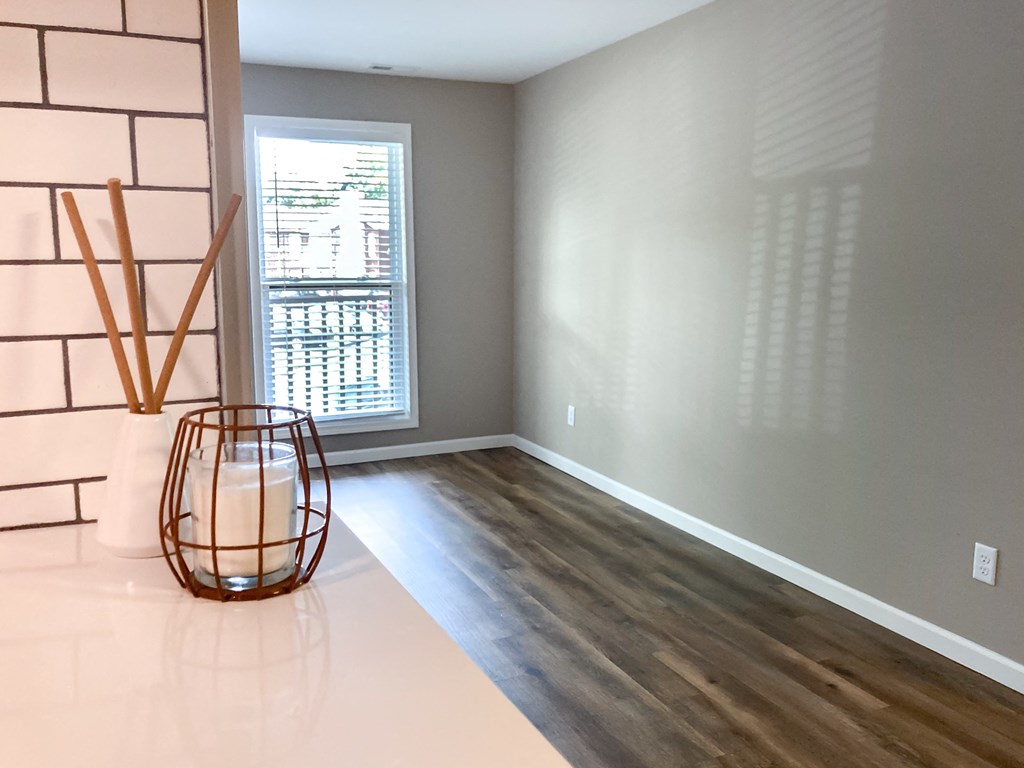 an empty living room with a large window and a table with a glass
