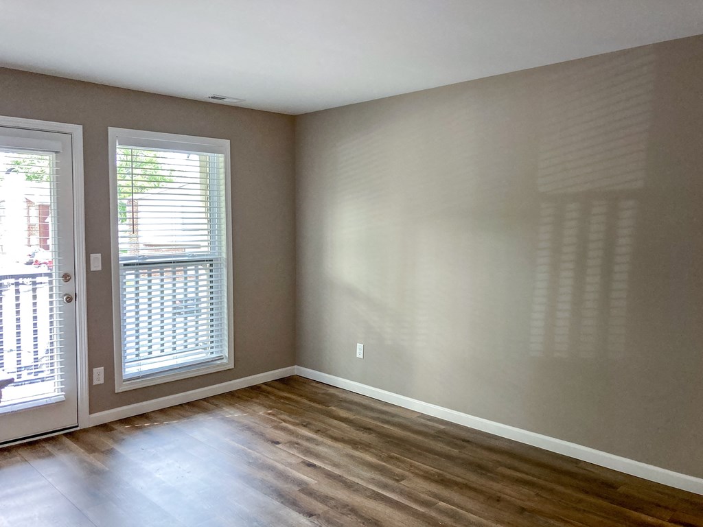 an empty living room with wood floors and a door to a balcony