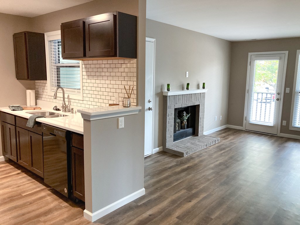 an empty living room with a fireplace and a kitchen