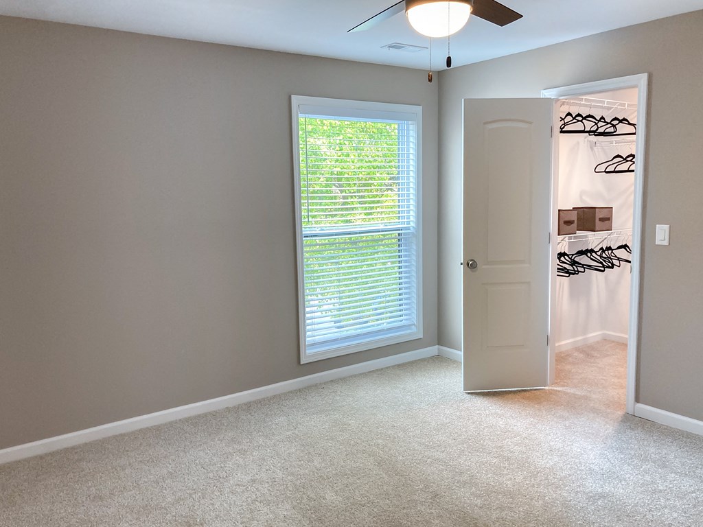 an empty bedroom with a window and a closet