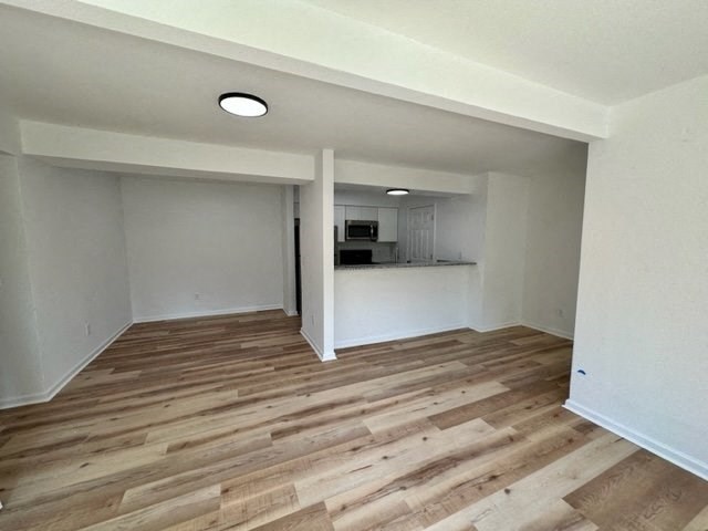 an empty room with a kitchen in the background