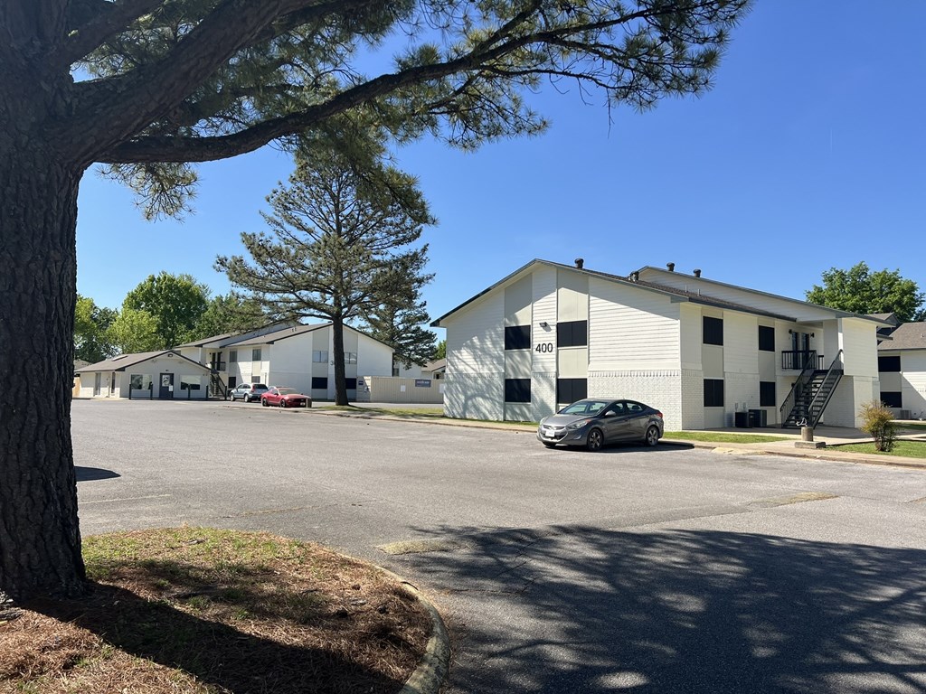 a parking lot with a car parked in front of a building at Mammoth at the Orchard Apartments, Rogers, AR 72756  