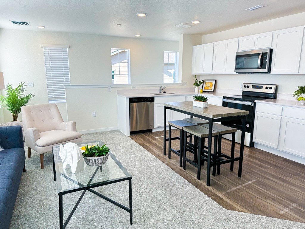 a living room with a kitchen and a table with chairs
