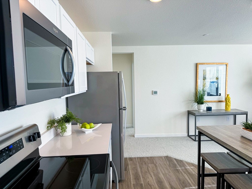 a kitchen with stainless steel appliances and a kitchen table with a microwave and a refrigerator