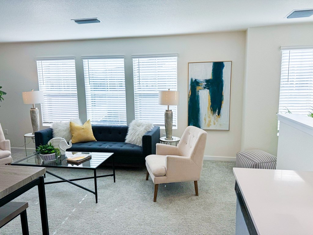a living room with a navy blue couch and white chairs