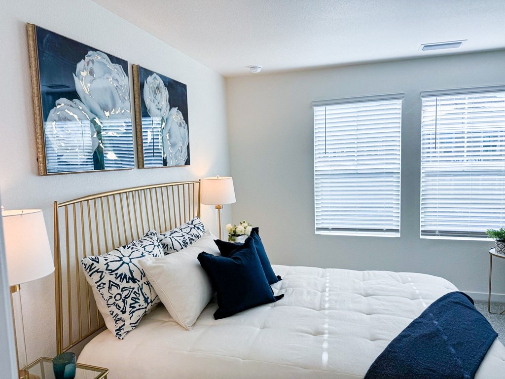 a bedroom with a large bed and two windows with blinds