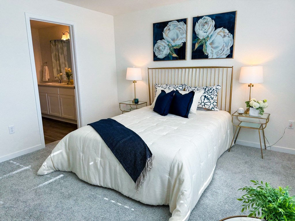 a bedroom with a white bed and two paintings on the wall