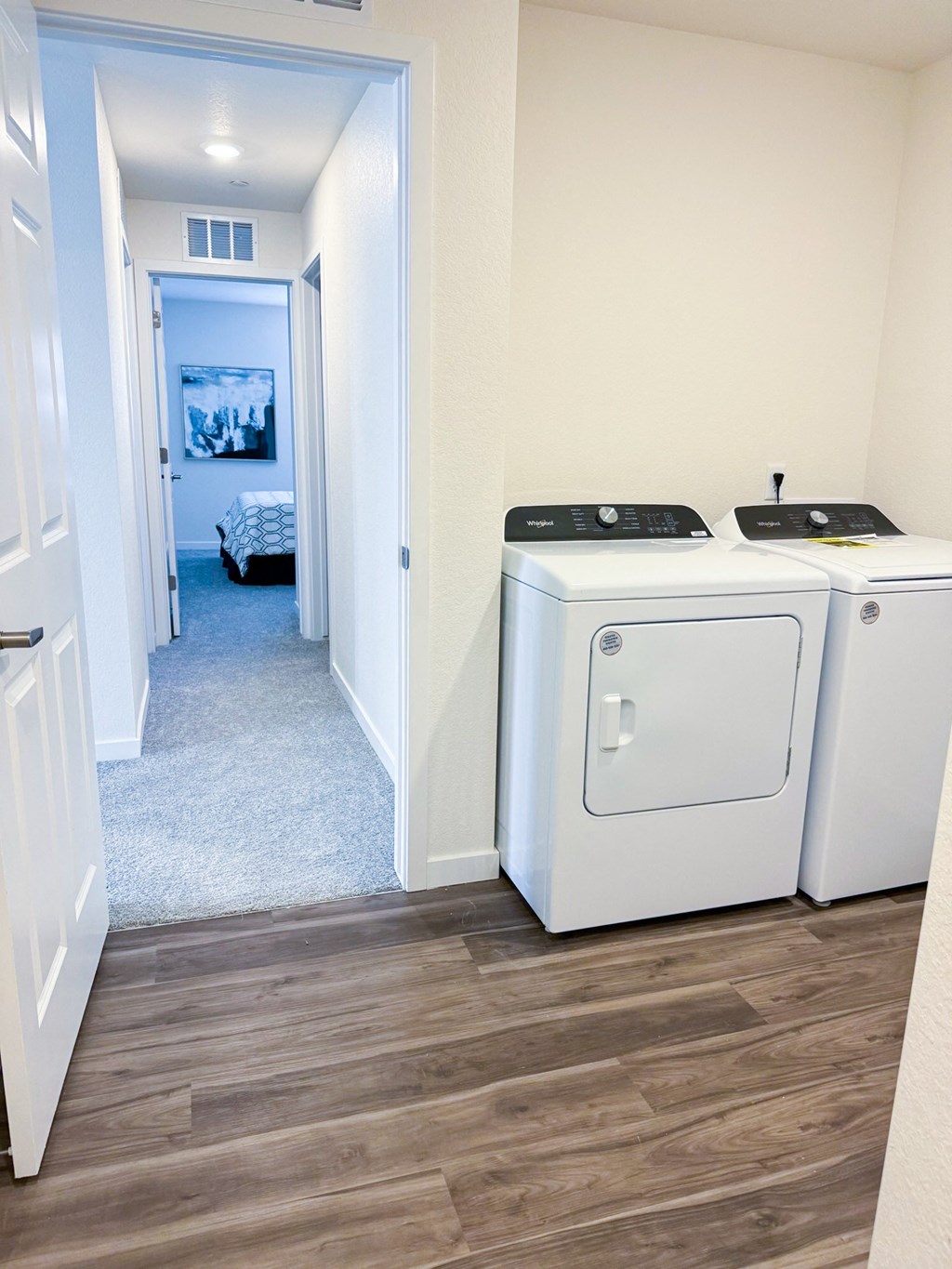 a white washer and dryer in a room with a hallway and a bedroom