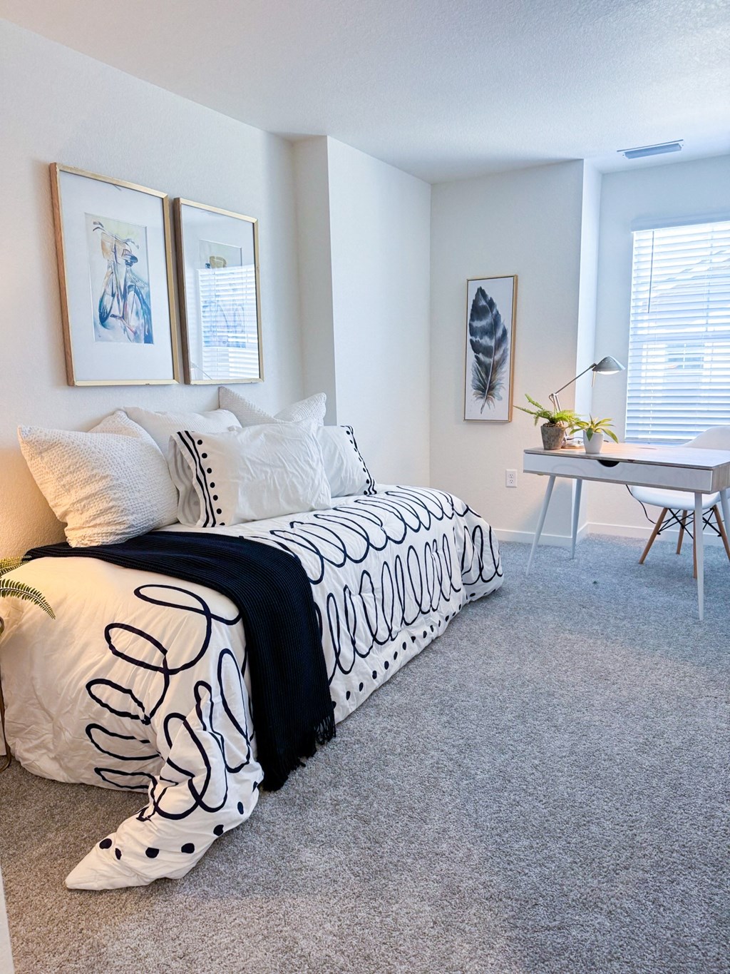 a bedroom with a bed with black and white pillows and a desk