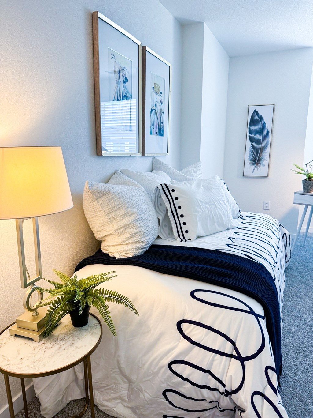 a bedroom with a bed with white and black pillows and a nightstand with