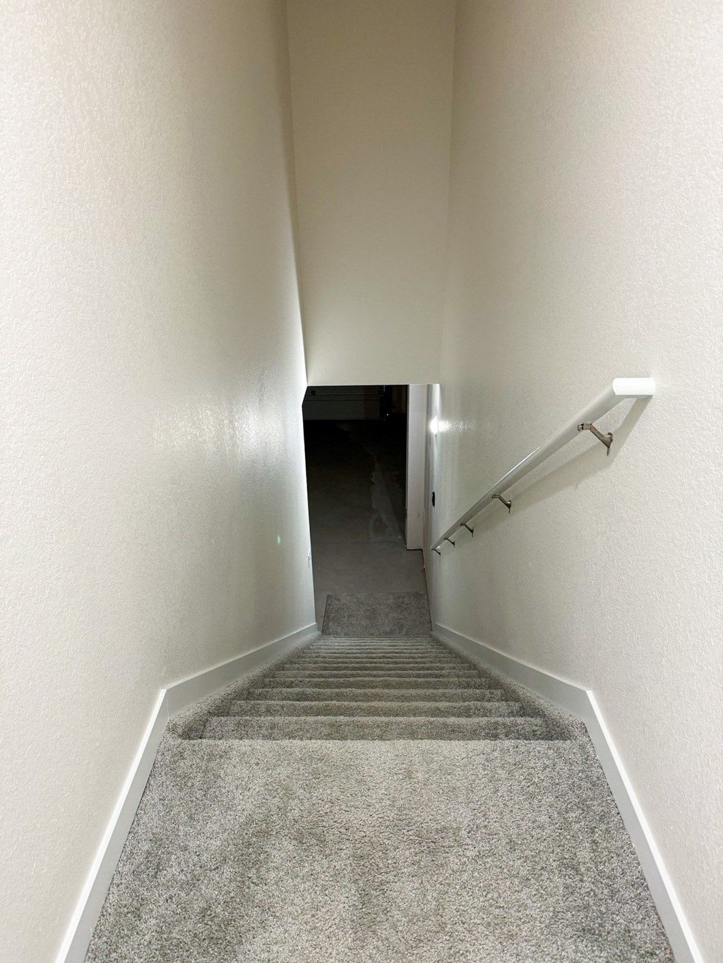 a view of a hallway with a carpeted floor and stairs