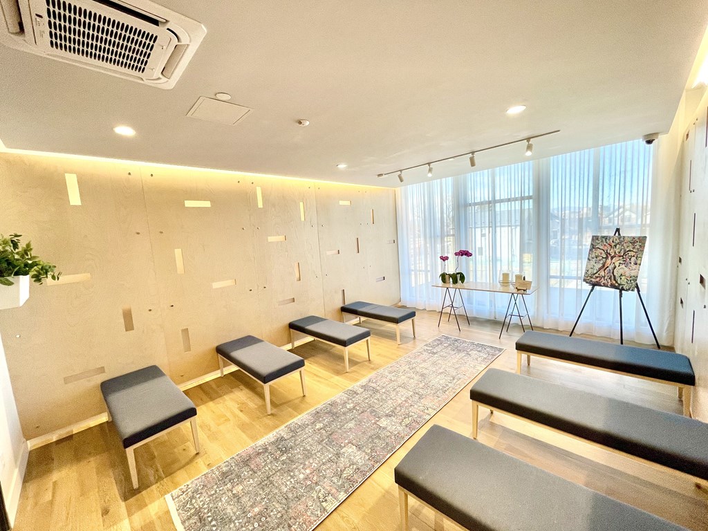 a yoga room with six black benches and a rug