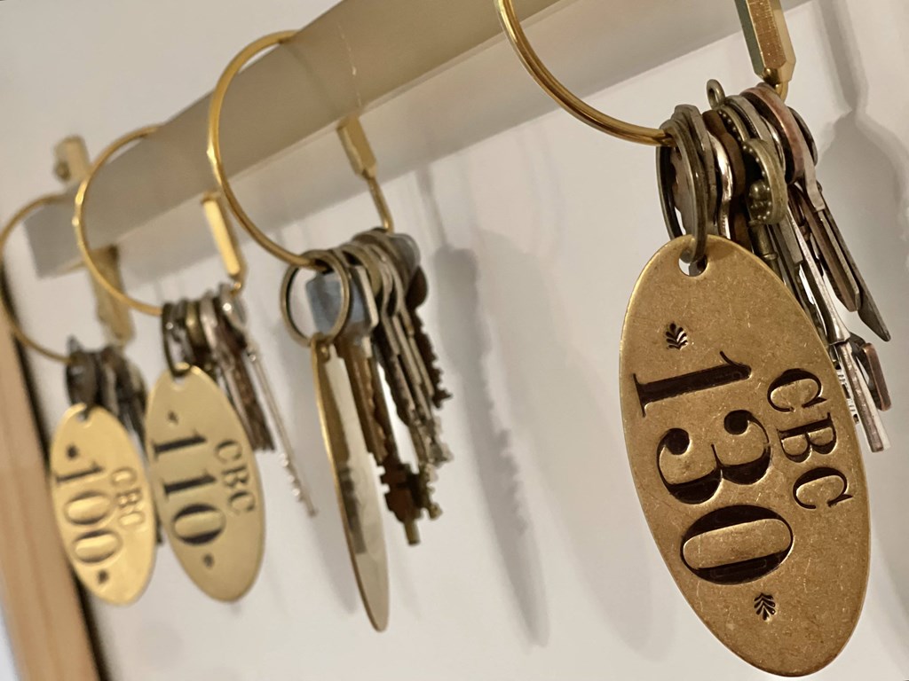 a row of keys hanging on a necklace chain with a guitar hero keychain on