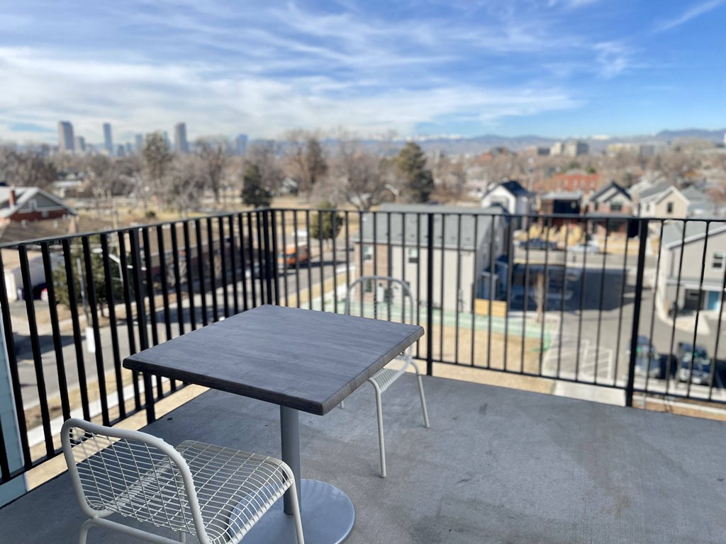 a table and chairs on a balcony with a view of the city